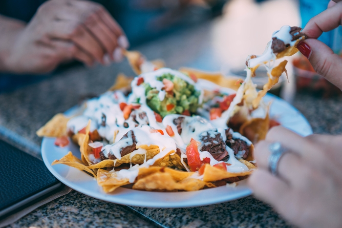 A plate of nachos being shared.