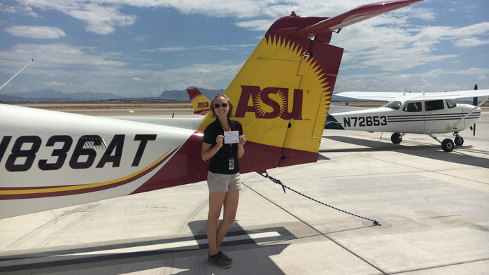 Megan in front of an ASU plane holding her commercial multi-engine license