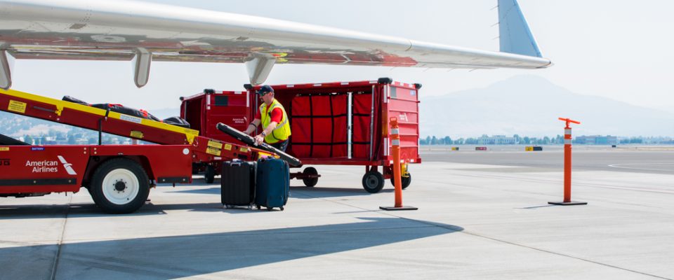 envoy airport agent employee on the ramp unloading baggage cart