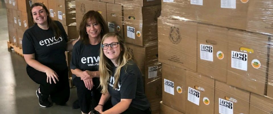 three female envoy employees pose for a photo while volunteering at the north texas food bank